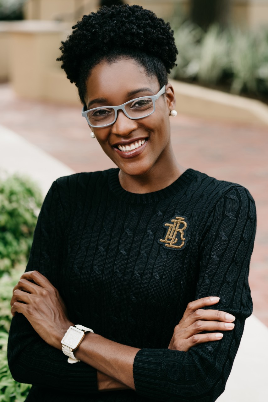 woman wearing glass smiling into camera with her arms crossed